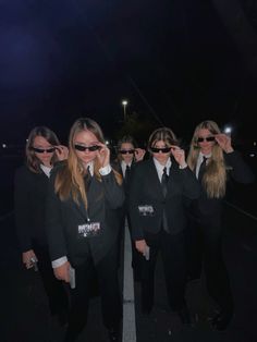 a group of women in suits and sunglasses are posing for the camera with one woman covering her eyes