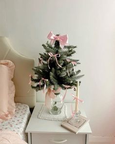 a small christmas tree sitting on top of a white table next to a pink bed