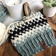 a knitted bag sitting on top of a wooden table next to a cup and plant