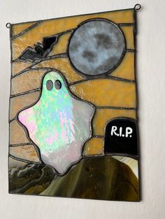 a stained glass wall hanging with a ghost and moon on it's back side