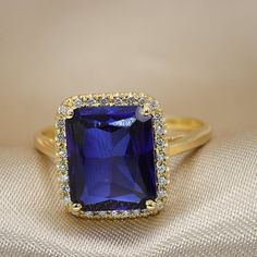 An Exquisite Blue Sapphire ring Halo set with diamonds.Flaunting as large impressive blue sapphire set in a high basket shimmer presence and luxury.Stand out wherever you go with this luxurious piece.It could be a wonderful engagement ring or a a luxurious fine piece of jewelry to wear on that special evening.Each gemstone is handpicked and inspected for the best color and clarity, The ring is beautifully finished and ready to give as a gift.• Made to Order, beautifully finished, Fully insured w Blue Emerald Cut Diamond Ring With Halo Setting, Formal Blue Diamond Ring With Halo, Formal Blue Crystal Ring With Halo Setting, Blue Emerald-cut Diamond Ring With Birthstone, Blue Emerald Cut Diamond Ring With Birthstone, Blue Sapphire Crystal Ring For Formal Occasions, Formal Sapphire Crystal Ring With Prong Setting, Formal Blue Sapphire Crystal Ring, Blue Cluster Ring With Halo Setting In Cubic Zirconia