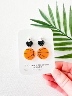 These bright and bold Neon Basketball Earrings are so fun for all you basketball fans ready to cheer on your favorite team or player! These earrings are made using acrylics that include a black glitter acrylic heart drop attached to a neon orange laser engraved basketball.  The total length of these earrings measure 1.75 inches tall and .85 inches wide. They are set using your choice of stainless steel Gold OR Silver Ball Posts with clear silicone backings OR nickel free and lead free ear wires Mom Basketball Clay Earrings, Basketball Earrings Diy, Ideas Arcilla, Neon Basketball, Basketball Earrings, Orange Basketball, Lover Earrings, Glitter Acrylic, Basketball Mom