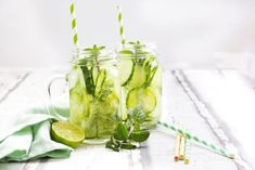 two mason jars filled with cucumbers and limes