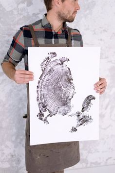 a man holding up a piece of paper with a tree stump cut out on it