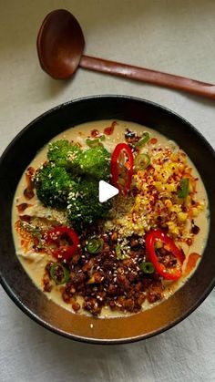 a bowl of soup with broccoli, peppers and other toppings in it