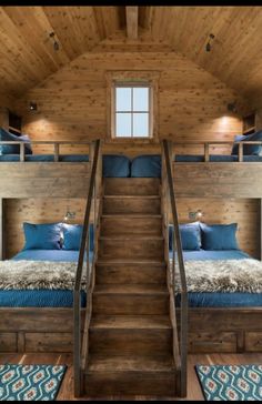 bunk beds with blue pillows and blankets in a loft style bedroom, along with stairs leading up to the second floor