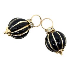 These 14k gold black enamel bead charms look great on a chain or charm bracelet—and also make perfect earring enhancers. The beads are ribbed with linear vertical gold enamel striping that makes a sharp contrast to the black beads. The beads are topped with sparkling glass stones and a quatrefoil adornment at the base. We’ve pictured them on our Vintage 14K Gold Small Hoop Earrings, as well as our Vintage 14K Gold Wire Choker. The versatility of these charms makes us think of them as a jewelry toy that allows you to dream up many different options for how to wear them.   The charms measure 15/16” x 7/16”. The opening of the bail measure 5.5 mm. There are six glass stones that measure 2mm each. Combined, the charms weigh 2.5 grams. They are unmarked and acid test as 14k gold. Wire Choker, Yellow Gold Diamond Earrings, Vintage Drop Earrings, Gold Caps, Small Hoop Earrings, Glass Charms, Gold Diamond Earrings, Pearl Charms, Amethyst Earrings