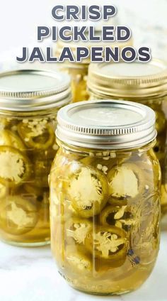 jars filled with pickled jalapenos sitting on top of a white table