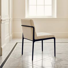 a white chair sitting in front of a window next to a tiled floor and wall