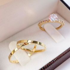 two gold wedding rings sitting in a box