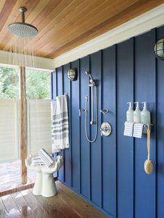 a bathroom with blue walls and wood flooring is shown in this image, there are towels hanging on the shower head