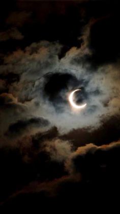 the eclipse is seen through clouds as it passes in front of a dark cloud filled sky