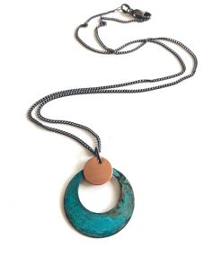 "Brass naturally oxidized with Verdigris patina. Pendant hangs from an oxidized silver chain. Measurement: 1\" Care: All of our patina pieces are sealed with a resin lacquer to help protect the oxidization, however we do recommend that you keep all patina pieces dry and away from water as it can further the oxidation process and potentially can alter the color. *Patina is a natural oxidation process so color shades may vary." Traditional Blue Patina Necklace, Artisan Metal Necklace With Patina, Silver Pendant Necklace With Patina, Unique Pendant Necklace With Patina, Bohemian Blue Patina Necklace, Handmade Ceramic Jewelry, Oxidized Silver, Ceramic Jewelry, Color Shades