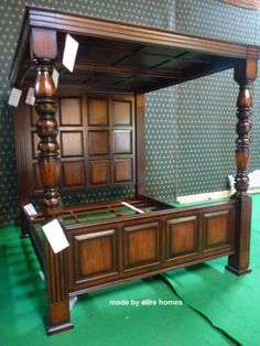 an antique bed frame with wooden posts and headboard on green carpeted flooring