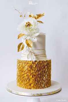 a white and gold wedding cake with flowers on top