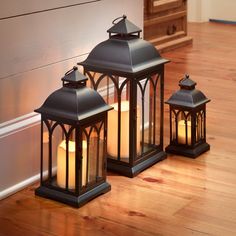 two black lanterns sitting on top of a wooden floor