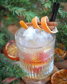 an orange and cinnamon drink in a glass with ice, cinnamon sticks, and sugar