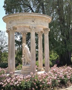 the statue is surrounded by pink flowers and trees