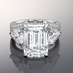 an emerald - cut diamond ring with three diamonds on the band and side stones, set in 18k white gold