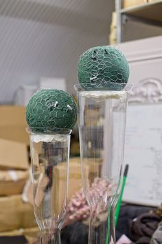 there are two green balls in the glass vases