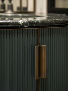 a kitchen counter with a black marble top and brass pulls on the cabinet door handles