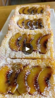 two pieces of cake on a white plate covered in powdered sugar and sliced peaches