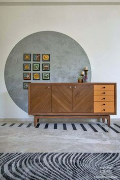 a modern sideboard in front of a wall with pictures on it and a zebra rug