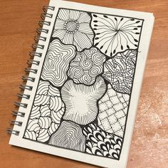 a spiral notebook with an abstract design on the front and back cover, sitting on a wooden surface