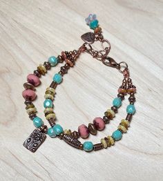 Beautiful double strand boho bracelet, one of my favs! This was created using Czech Picasso glass beads in opaque dusty rose, light aqua blue, cream, and dark beige.  I have also used  antique copper accent beads throughout, and an antique copper charm etched with a lotus flower.  The extender chain is finished with a small copper heart charm, and a Czech bell flower bead dangle.  This beautiful bracelet is perfect for everyday, and makes a wonderful gift! Bracelet best fits a wrist size between 6-3/4" - 7-1/2".  If a longer extender is needed, please leave a note at checkout. Matching earrings: https://www.etsy.com/listing/1659804395/antique-copper-lotus-flower-earrings?click_key=3c3d06fb1210a703d14f4e975a7a44914a5b9731%3A1659804395&click_sum=ac821664&ref=shop_home_active_1&frs=1&sts=1 Th Copper Heart, Jewelry Styles, Gift Bracelet, Hippie Bracelets, Multi Strand Bracelet, Light Aqua, Boho Bracelet, Glass Bracelet, Dark Beige