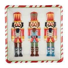 two wooden nutcrackers are on display in a glass tray with candy canes