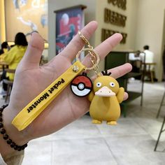 a hand holding a pokemon keychain with a pokeball charm attached to it