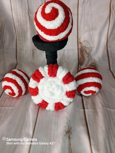 a red and white crocheted ball on a black stand