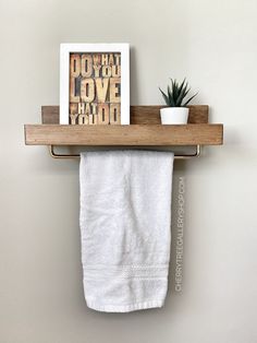 a white towel hanging on a wooden shelf next to a potted plant and framed photograph