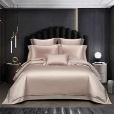 a large bed with black headboard and beige comforter in a dark colored room