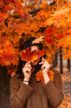 a woman is holding leaves in front of her face