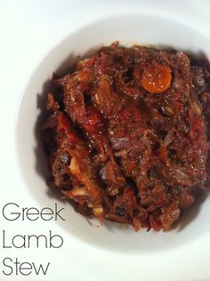 a white bowl filled with food on top of a wooden table and the words greek lamb stew above it