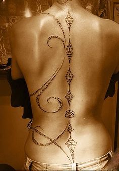 the back of a woman's body with an intricate tattoo design on her lower back