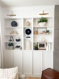 a living room filled with lots of white bookshelves covered in vases and plants