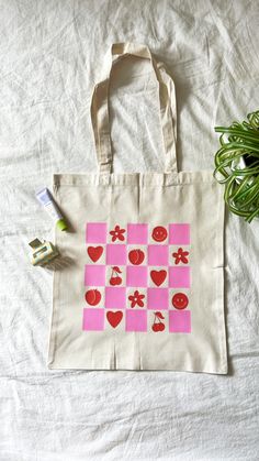 a tote bag sitting on top of a bed next to a plant