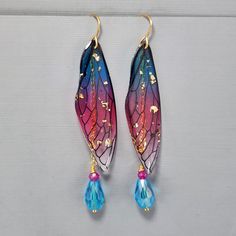 "Fairy Wing Earrings Blue Wing Pink Wing Fairy Wings Earrings Blue Crystal Teardrop Earrings Gold Flake Wings Dragonfly Wing Earrings These super fun light weight earrings are so pretty.  I connect the resin wings to the ear wire and hang a glass tear drop and glass crystal from a gold plated chain.  The beads are wire wrapped for added security.  The earrings hang 2 3/4\" from the gold plated ear wires.   They ship with rubber backs to prevent loss. They ship in a delightful organza bag perfect for gift giving." Whimsical Blue Drop Earrings, Blue Fairy Jewelry For Party, Blue Fairy-style Jewelry For Party, Whimsical Blue Earrings For Party, Whimsical Blue Hand Painted Earrings, Whimsical Hand Painted Blue Earrings, Fairy Wings Earrings, Drawing Body Proportions, Fairy Wing Earrings