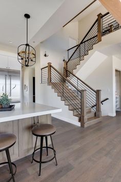 a kitchen with two stools next to a counter top and an open stair case