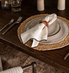 a place setting on a wooden table with white plates and silverware, napkins and utensils