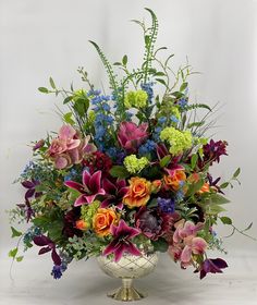 a vase filled with lots of colorful flowers on top of a white tablecloth covered floor