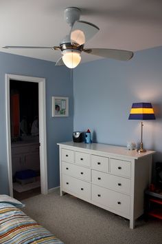 a bedroom with blue walls and a ceiling fan