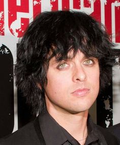 a close up of a person with black hair and green eyes wearing a black shirt