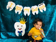 a little boy sitting in front of a blue backdrop brushing his teeth