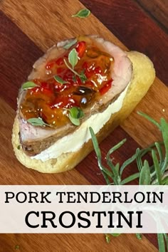 a piece of bread with meat and vegetables on it sitting on a cutting board next to a sprig of rosemary