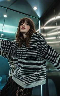 a woman standing in front of a mirror wearing a black and white sweater with stripes