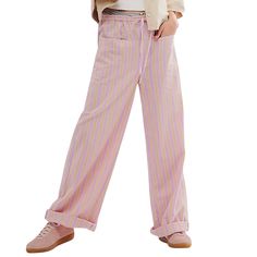 a woman in pink and white striped pants standing with her hands on her hips, looking at the camera