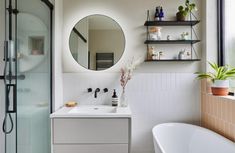 a bathroom with a sink, mirror and bathtub next to a shower stall filled with plants